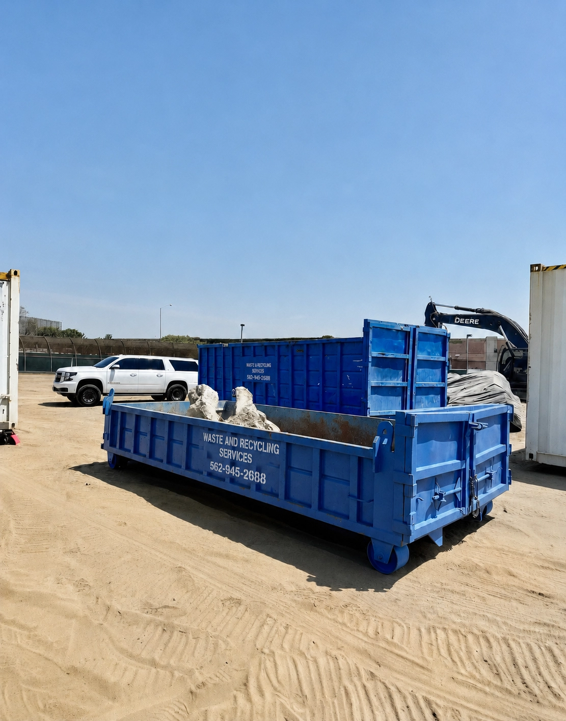 WRS blue 10-yard lowboy roll-off dumpster with concrete debris at a job site